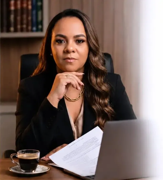 Dra. Wanessa Matias à mesa de trabalho, com documentos e um café